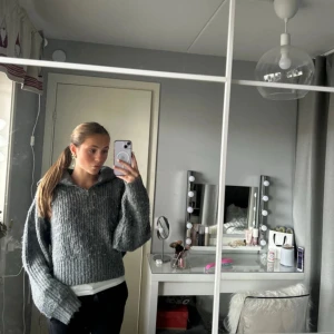 Grå stickad tröja från Gina Tricot - Säljer en mysig grå stickad tröja från Gina Tricot. Tröjan har en dragkedja framtill och en hög krage som ger extra värme. Perfekt för kyliga dagar! Köpt för 600kr och använd ett fåtal gånger❤️