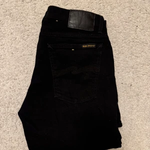 Nudie Jeans - Snygga svarta jeans från Nudie Jeans i modellen Skinny Lin. De har en tight passform och är tillverkade i en bomullsblandning med elastan för extra komfort. Perfekta för en stilren look. Strl 32/32