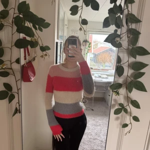 Randig stickad tröja i rosa, beige och grå - Säljer en mysig stickad tröja med breda ränder i rosa, beige och grå. Tröjan har långa ärmar och en rund halsringning. Perfekt för kyligare dagar!