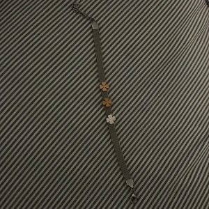 Armband med blommor i guld och silver - Elegant armband med en kedja i silverfärg och tre blommor i guld och silver. Perfekt för att lägga till en subtil touch av elegans till din stil. Armbandet har en justerbar kedja för perfekt passform. Helt nytt aldrig använt. Från Edblad 