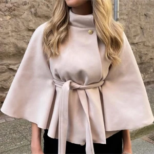 Beige poncho  - Säljer en superfin beige kappa med knytband i midjan. Den har en elegant cape-stil och en knappdetalj vid halsen. Helt oanvänd med prislapp på!