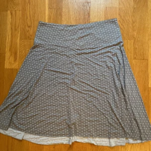 Grå prickig kjol från Funny by Helen H - Säljer en superfin grå kjol med vita prickar från Funny by Helen H. Kjolen har en bekväm passform och är perfekt för både vardag och fest. Den är gjord i ett mjukt material som känns skönt mot huden. Passar perfekt till sommaren eller våren!