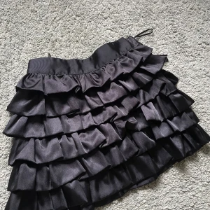 Svart volangkjol - Säljer en superfin svart volangkjol. Perfekt för fest eller nyår! Kjolen har en dragkjedja i sidan och kjolen är i storlek 36. 