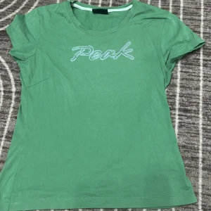 Grön t-shirt från Peak - Säljer en snygg grön t-shirt från Peak i bomull. Det är storlek M men passar mig som är xs/S. Kortärmad och i bra skick, Passar perfekt till jeans eller shorts!