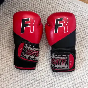 Säljer ett par röda boxningshandskar från Fighter i storlek 12 oz. De är gjorda för fighters och har en cool design med svart och röd färg. Perfekta för träning och sparring. Kardborreband för enkel justering och bra passform. Använda men i bra skick!