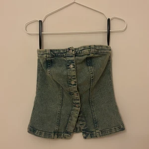 Jeanskorsett med knappar - Snygg jeanskorsett i en cool tvättad look. Den har knappar framtill och en stilren design som passar perfekt för en trendig outfit. Perfekt för både vardag och fest!