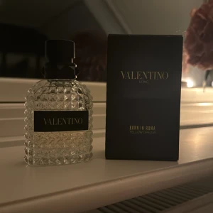 Valentino Uomo Born in Roma Yellow Dream - Säljer en lyxig parfym från Valentino, 'Uomo Born in Roma Yellow Dream'. Flaskan är elegant med ett mönster av små nitar och en svart kork. Doften är modern och stilren, perfekt för speciella tillfällen. Kommer i originalförpackning. Passa på att köpa denna exklusiva doft!