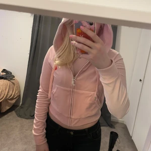 Juicy couture  - Säljer en superfin rosa hoodie från Juicy Couture i storlek S. Den har en snygg fjärilsbrodering och text på ryggen. Hoodien är croppad och har dragkedja framtill. Perfekt för en avslappnad stil eller en chill dag ute. 🦋