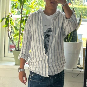 Randig skjorta  - Vit grå randig skjorta som har varit använda, sitter snyggt både långärmat och när man rullar upp de! 