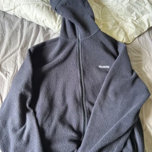 Vetements Fleece Gimp - Säljer en mörkblå fleecejacka från Vetements i unisexmodell. Den har en dragkedja framtill och en cool vit logga på ryggen. Perfekt för kyliga dagar och ger en avslappnad stil. Jackan är i mycket bra skick och passar både höst och vår.