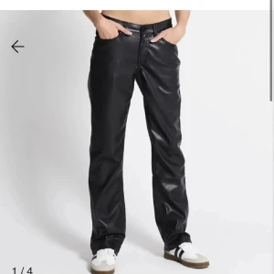 Svarta skinnbyxor - Säljer ett par snygga svarta skinnbyxor i mycket bra skick. De är högmidjade och har en straight passform som ger en cool look. Perfekta för höst och vinter, och funkar lika bra till vardags som till fest. Byxorna har knappar och dragkedja framtill.