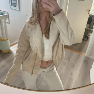 Beige mockajacka - Säljer en snygg beige mockajacka i mycket bra skick. Jackan har en cool bikerstil med dragkedja och långa ärmar. Perfekt för höst och vår, och den är i en normal passform. Storleken är 170 men jag använder xs-s och den passar mig som ni ser.