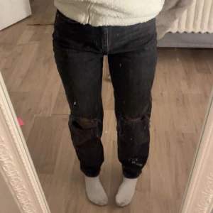 Svarta jeans med slitningar - Säljer ett par svarta jeans med coola slitningar på knäna. De har en tight passform och är perfekta för en avslappnad stil. Jeansen är i bra skick och passar till både vardag och fest. Perfekta för höst och vinter!