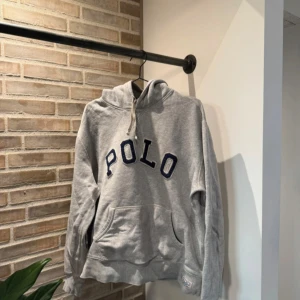Polo Hoodie - Grå polo hoodie i storlek XL men sitter som M-L. Den har inga synligheter på användning men är använd. Skick 9/10.  Måtten är 54 bredd 63 längd          Hör av dig vid frågor!