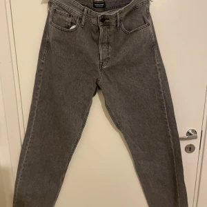 Grå jeans från Jack & Jones som är i ny skick - Säljer ett par grå jeans från Jack & Jones i storlek 32/32. De har en klassisk femficksdesign och är i mycket bra skick. Har använt det några gånger men det finns inga täcken på användning så jag har tagit hand om den väldigt väl. Nypris ligger på ungefär 400 kr