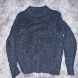 Mysig blå stickad tröja - Säljer en supermysig blå stickad tröja i bra skick. Perfekt för kalla höst- och vinterdagar. Tröjan har långa ärmar och en klassisk rund halsringning. Den är både stilren och bekväm, perfekt för att hålla värmen i stil. Passar till både vardag och mysiga hemmakvällar