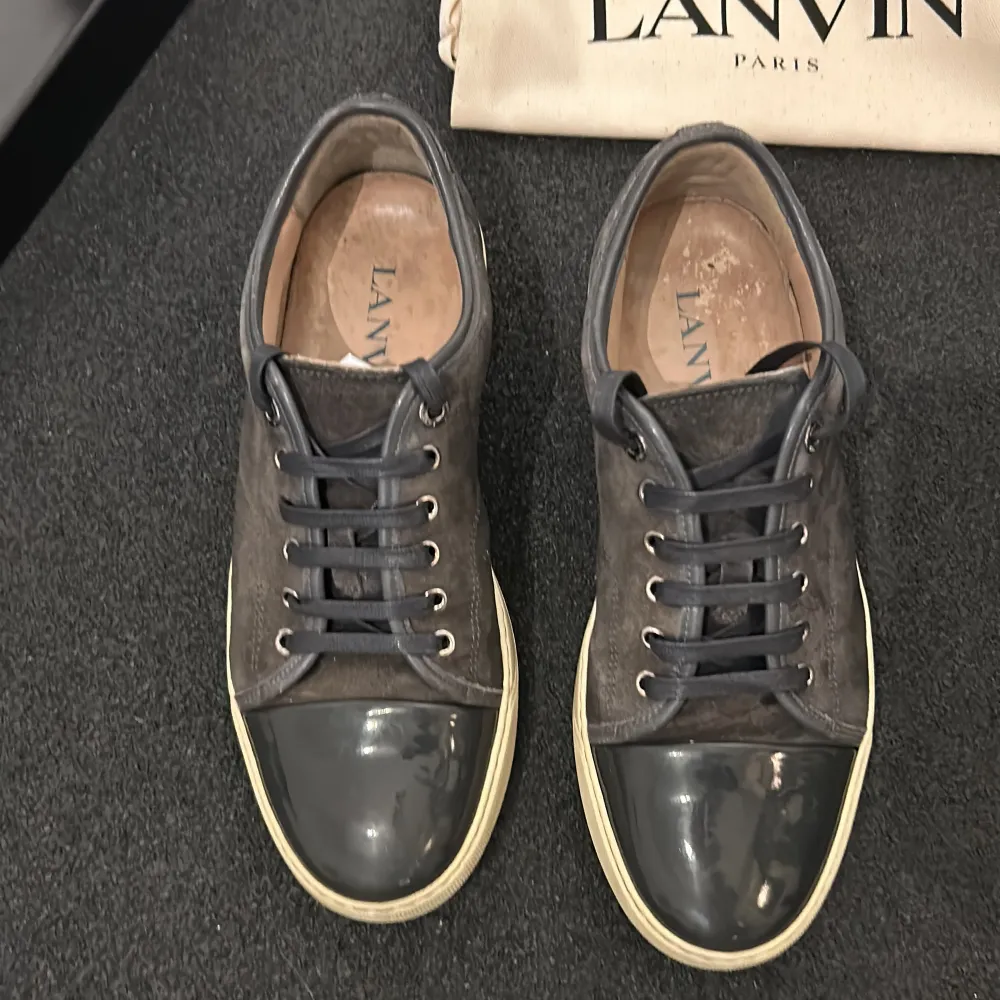 (Väldigt öppen för byten) Tja, Säljer ett par stilrena grå sneakers från Lanvin i bra skick. Skorna har en snygg kombination av mocka och skinn med svarta snören och en vit sula. Snörena är sprillans nya och har aldrig använts. Perfekta för både vardag och fest! Även väldigt varma nu i vintertider. Kommer med originalkartong, 2 dustbags, extra snören och äkthetsbevis+tack från där ja köpte de (Care of carl) nypris 5000kr. Allt OG medföljer alltså!. Skor.