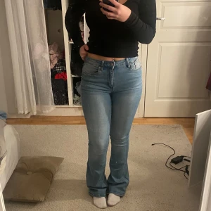 Ljusblå bootcut jeans - Säljer ett par ljusblå bootcut jeans i bra skick. De är högmidjade och har en klassisk femficksdesign med dragkedja och knapp framtill. Perfekta för både vardag och fest!