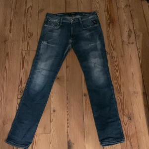 Blå jeans från Replay - Säljer ett par snygga blå Replay Hyperflex Anbass jeans i bra skick. De har en cool, sliten look med ljusare partier och är superbekväma tack vare stretchmaterialet. Perfekta för både vardag och fest! 🕺