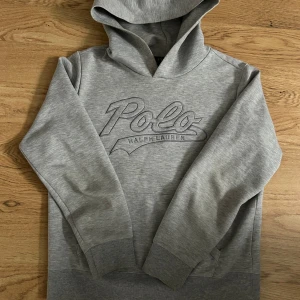 Grå hoodie från Ralph Lauren - Säljer en snygg grå hoodie från Ralph Lauren i storlek L (14-16 år) så mer som en XS. Den har en stor Polo-logga på bröstet och en magficka. Superbekväm och i mycket bra skick!