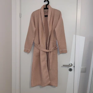 Rosa våfflad morgonrock - Riktigt fin morgonrock i härlig våfflad kvalitet säljes. Känns lyxig på. Perfekt för en kylig morgon eller efter en dusch. Storlek S-M men passar  även XS. Aldrig använd. 