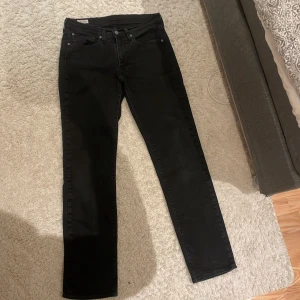 Svarta jeans från Levi's - Snygga svarta raka jeans från Levi's med klassisk femficksdesign och knappgylf. Perfekta för en stilren look. Passar till många olika outfits och tillfällen.