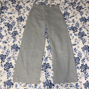 Grå byxor från Aware - Snygga grå byxor från Aware med en loose passform. De har en hög midja och raka ben, vilket ger en avslappnad stil. Perfekta för en trendig look. Obs! några fläckar och lite slitet längst ned på benet.