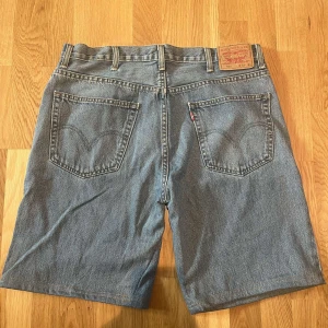 Blå jeansshorts från Levi's - Säljer ett par klassiska blå jeansshorts från Levi's. De har en normal passform med fem fickor och knappgylf. Perfekta för en avslappnad stil.