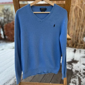 Blå tröja från Ralph Lauren - Säljer en stilren blå V neck tröja från Ralph Lauren i Pima bomull. Tröjan har en klassisk v-ringning och det ikoniska broderade logotypen på bröstet. Perfekt för vintern! Storlek: Xs. Kom med bud!