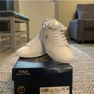  Vita  sneakers från Polo Ralph Lauren - Säljer ett par helt nya oanvända vita sneakers från Polo Ralph Lauren. (Kostar runt 1100 kr nya i butik). Skorna har en klassisk design med snörning och den ikoniska loggan på sidan. Kommer i orginal kartong. Bara att höra av sig om man har frågor.