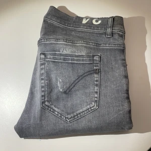 Grå Dondup jeans - Snygga populära dondup jeans i modellen George, stl 34. Riktigt feta detaljer och slitningar. Skick 8.5/10, små tecken på användning. Skriv vid minsta fråga eller fundering! Pris inte hugget i sten så kom med bud!