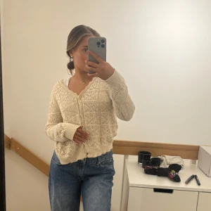 Beige stickad kofta - Säljer en söt beige stickad kofta med vackert spetsmönster. Koftan har långa ärmar och knappar framtill, perfekt för lager-på-lager under kyligare dagar.sitter mer som s