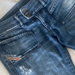 Blå jeans från Diesel - Snygga blå jeans från Diesel med en cool tvätt och slitna detaljer. De har en klassisk femficksdesign och en knappgylf. Perfekta för en avslappnad stil.