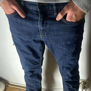 Blå jeans från Boss - Säljer ett par snygga blå jeans från Boss. De har en klassisk femficksdesign och en bekväm passform. Perfekta för en stilren look. Storleken är liten skulle säga att dem passar runt 30/32 31/32