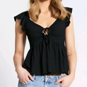 Svart blus med knytning lager 157 - Snygg svart blus med knytning framtill och volangdetaljer vid ärmarna. Aldrig använd (bilden med den vita blusen är endast för att se hur blusen ser ut på) ❤️❤️ser konstig ut på bilden men den är aldrig använd och är helt svart