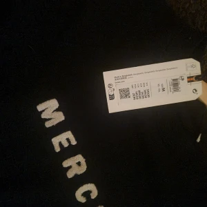 Mörkblå tröja med texten 'MERCI' - Säljer en mörkblå tröja med texten 'MERCI' i vitt på bröstet. Tröjan har långa ärmar och en rund halsringning. Perfekt för en avslappnad stil.