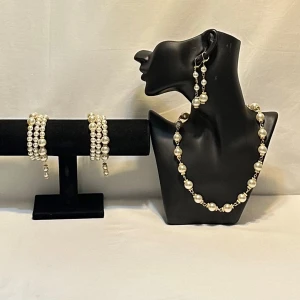 Pärlsmyckeset med halsband, armband och örhängen - Elegant smyckeset med pärlor som inkluderar ett halsband, armband och örhängen. Perfekt för att ge en klassisk touch till din outfit. Pärlorna är vita och ger en tidlös känsla.Ett par örhängen och ett par armband plus en halsband handgjorda mycket mycket fint nytt oanvänd 