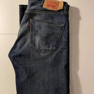Levi's 501 jeans - Klassiska Levi's 501 jeans i mörkblå denim. De har en rak passform och fem fickor med knappgylf. Perfekta för en avslappnad stil. Mycket bra skick!