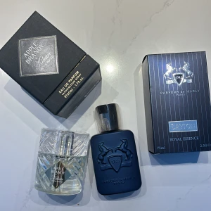 Parfymset från Kilian och Parfums de Marly - Två exklusiva parfymer: 'Apple Brandy' från Kilian i en elegant glasflaska och 'Layton' från Parfums de Marly i en stilren mörkblå flaska. Båda kommer i sina originalförpackningar, vilket ger en lyxig känsla.