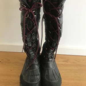 Svarta vinter stövlar kängor Tommy Hilfiger Stl 38 - Snygga vinterstövlar från Tommy Hilfiger. Stövlarna är svarta och har en snygg design med snörning. Passar olika vader då snörningen är justerbar. De är perfekta för kalla vinterdagar. Använda ett fåtal gånger, är i mkt bra skick, dock kan dragkedjan kärva lite vid ett ställe, lite skav på ett ställe under sulan, annars i så gott som nyskick. Nypris 3500:-