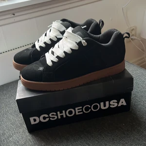 Court grafikk dc shoes - Snygga svarta sneakers från DC Shoes med vit snörning och brun sula. Använda fåtal gånger. Str 44 men dom passar mig som normalt har 45,46 