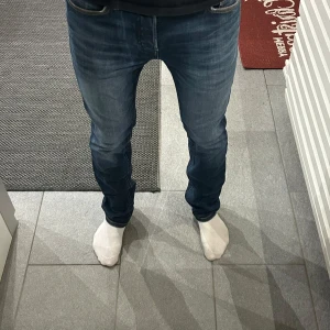 Jeans Jack&jones  - Snygga blå slim straight jeans med klassisk design. De har en midwaist passform och är perfekta för en stilren look. Jeansen har fem fickor och orange sömmar som ger en fin kontrast.