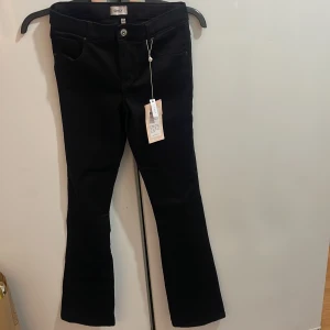 Svarta bootcut byxor från Only - Snygga svarta bootcut byxor från Only. Byxorna har en klassisk design med knappar och dragkedja framtill. Perfekta för en stilren look.