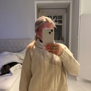 Beige stickad tröja med polokrage - Mysig beige stickad tröja med polokrage. Perfekt för kyliga dagar med sin varma och bekväma design. Tröjan har långa ärmar och ribbade kanter för extra komfort. Prislapp sitter på!