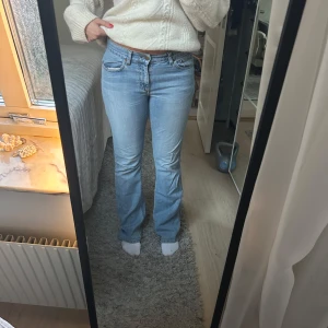 Ljusblå bootcut jeans - Säljer ett par ljusblå bootcut jeans med klassisk femficksdesign. Jeansen har en bekväm passform och är perfekta för en avslappnad stil. De har en knapp och dragkedja framtill. Lågmidjade jeans. Midjemått 78cm innerbenslängd 86