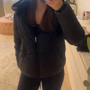 Svart pufferjacka med huva - Säljer en super fin svart pufferjacka från VeroModa! den är i bra skick, den har däremot lite små ”fläckar” på insidan av jackan, men skulle Inte säga att det är något som syns när jackan är på!💕går att justera i midjan! Skriv vid frågor 🥰🥰