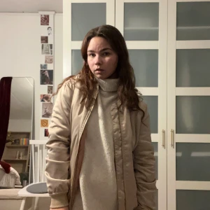 Beige bomberjacka från Bik Bok - Snygg beige bomberjacka från Bik Bok i storlek S. Jackan har en klassisk bomberstil med ribbade muddar och dragkedja framtill. Perfekt för en stilren look.
