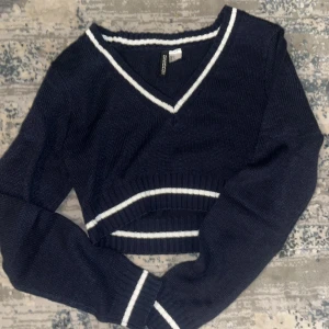 Mörkblå croppad tröja med vita detaljer - Snygg mörkblå croppad tröja från Forever 21 med vita ränder vid v-ringningen och nederkanten. Tröjan har långa ärmar och är perfekt för en trendig look.