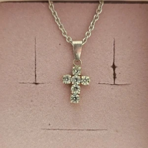 Silverfärgat halsband med korshänge - Elegant halsband med ett korsformat hänge dekorerat med glittrande stenar. Kedjan är i silverfärg och har en klassisk design som passar till många tillfällen. Köpt från Guldfynd. Ingen förpackning tillkommer då halsbandet är köpt utan förpackning.