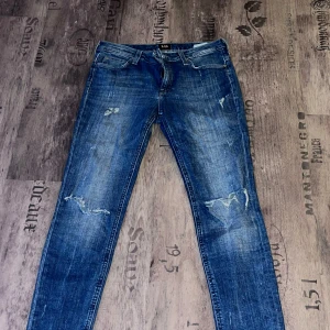 Blå jeans från Lee - Snygga blå jeans från Lee med slitna detaljer. Perfekta för en avslappnad stil.